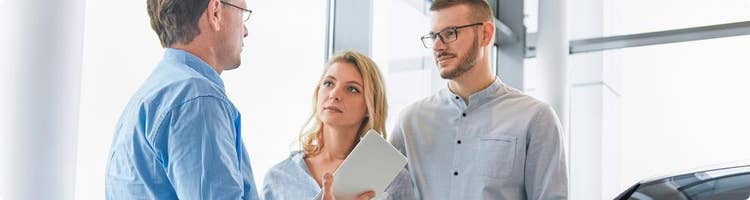 car dealer chats with couple