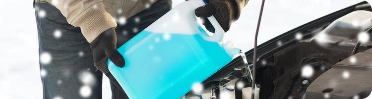 man pours windshield fluid in the snow