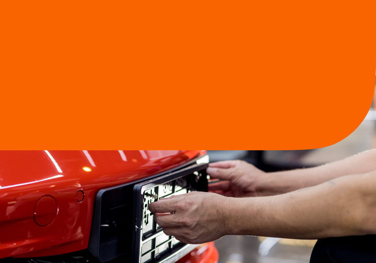 A man puts a new license plate on his vehicle.