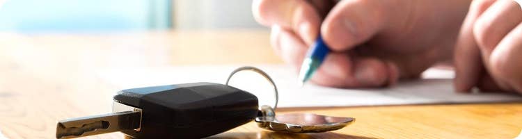 close up hand signing auto loan deal
