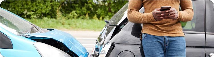 man uses phone in front of car accident