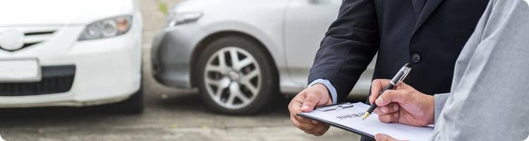 driver signs document next to two cars that have collided