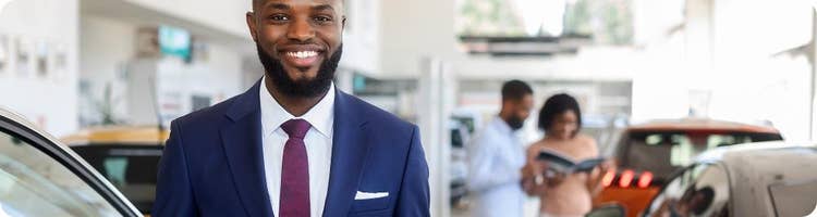 car dealer with cars and customers smiling