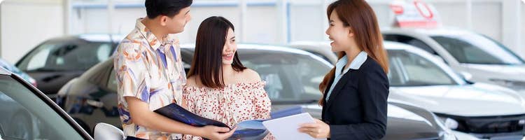 car dealer shows customers paperwork