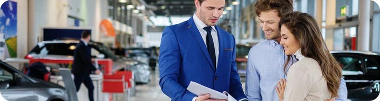 car dealer shows happy couple paperwork