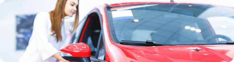 young woman looks at new red car